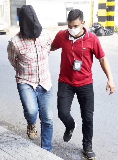 El alemán Reiner Helmut Oberüber, esposado y encapuchado, es acompañado por un policía.