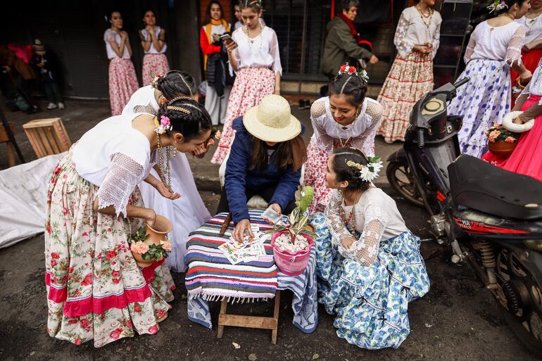 Una pruebera (mujer que tira las cartas) lee el futuro a unas bailarinas en el marco de la fiesta de San Juan, hoy, en el Mercado 4 en Asunción (Paraguay). Paraguay celebra este viernes la tradicional fiesta de San Juan con música paraguaya, comidas típicas y juegos tradicionales en el Paseo de los Yuyos del Mercado 4 en Asunción. EFE/ Nathalia Aguilar
