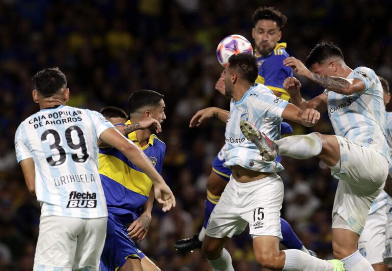 El zaguero paraguayo Bruno Valdez despeja el balón superando en el salto a jugadores del Atlético Tucumán.