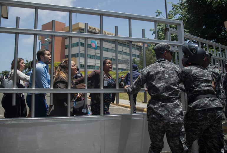 Empleados del Ministerio de Ambiente dominicano intentan salir del predio durante el disparo en Santo Domingo.
