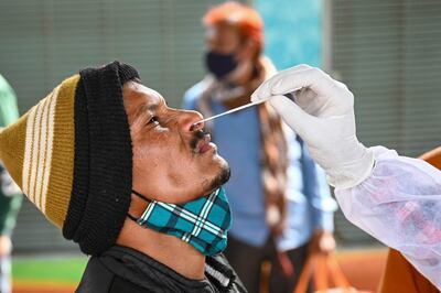 Un trabajador de la salud toma una muestra para una prueba de covid-19 de un hombre en Bombay, India.