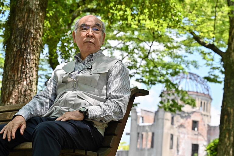Masao Ito, sobreviviente de la bomba atómica de 82 años, durante una entrevista con AFP en el parque frente al Domo de la Bomba Atómica (atrás a la derecha) en Hiroshima.