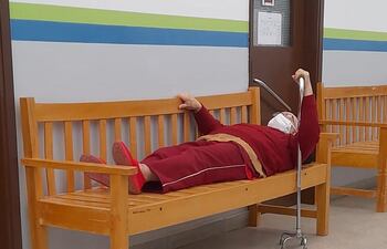 Una persona de la tercera edad que espera ser atendida se acostó en el banco debido a la excesiva demora en la atención.