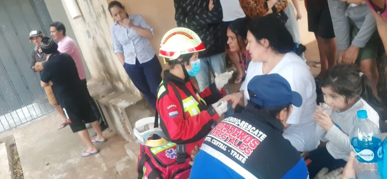 Bomberos dando los primeros auxilios a los afectados por el derrumbe de una estructura edilicia en Ñemby. (gentileza).