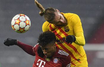Duelo aéreo por el balón entre el español Oscar Mingueza (d), del Barcelona, y el francés Kingsley Coman, del Bayern, durante el partido jugado ayer en Munich.