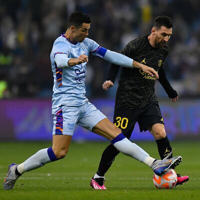 Cristiano Ronaldo (i) extiende la pierna izquierda para bloquear un intento de Lionel Messi.