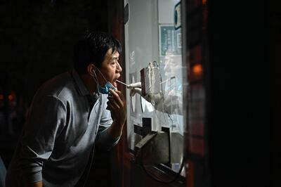 Un trabajador de la salud toma una muestra de saliva de un hombre para una prueba de covid-19 en Pekín, China.