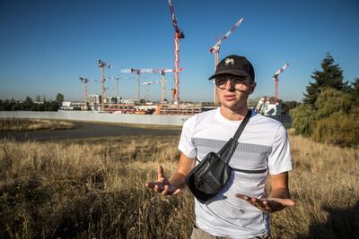 Arthur, miembro del colectivo ecologista 'Saccage 2024', habla frente a las grúas en las obras de construcción de la media village de los Juegos Olímpicos de París 2024 en construcción en el jardín del 'Aire des Vents' en Dugny.