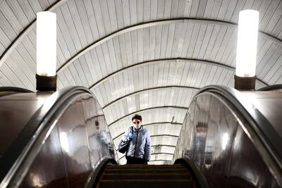 Una mujer con una máscara facial y guantes se sube a una escalera mecánica en la estación de metro Savyolovskaya en el primer día de uso obligatorio de máscaras y guantes en el transporte público de Moscú, el 12 de mayo de 2020.