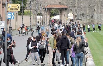 turistas se reúnen en la plaza Miracle y la torre inclinada de Pisa.