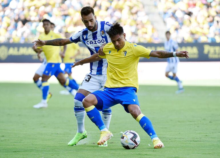 El paraguayo Santiago Arzamendia, del Cádiz, cubre la posesión del balón ante el español Brais Méndez, de Real Sociedad.