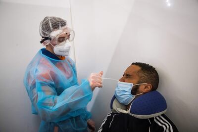 Un trabajador de la salud de la 'Protección Civil' con equipo de protección recoge una muestra de hisopo nasal de un pasajero que llega de un vuelo internacional en las llegadas internacionales del aeropuerto de París-Charles de Gaulle en Roissy, Francia.