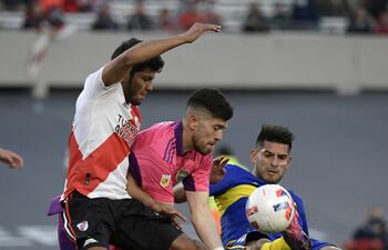 Robert Rojas en acción ofensiva ante el arquero de Boca Agustín Rossi y el zaguero Carlos Zambrano, durante el partido que River ganó ayer 2-1. (AFP).
