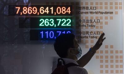 Un hombre observa un cartel que muestra la cantidad de habitantes del mundo, los nacimientos y las muertes en el Museo de Historia Natural de Shanghai, en China.