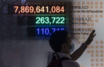 Un hombre observa un cartel que muestra la cantidad de habitantes del mundo, los nacimientos y las muertes en el Museo de Historia Natural de Shanghai, en China.