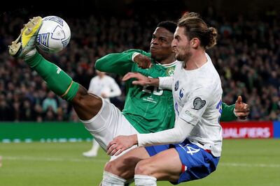 El irlandés Chiedozie Ogbene puntea el balón ante el francés Adrien Rabiot.
