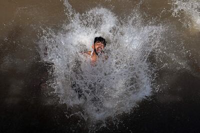 Un muchacho se refresca del calor en un canal de Lahore.