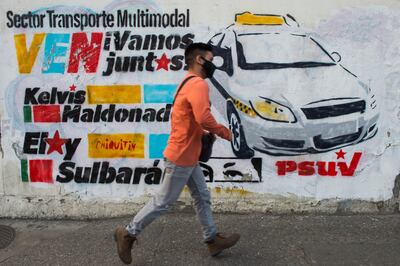 Un hombre camina junto a un mural con los nombres de candidatos a la Asamblea Nacional de Venezuela, en Caracas.