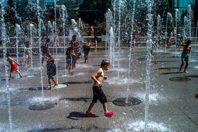 Niños juegan en una fuente para refrescarse en el Parque Andre Citroen en París, Francia, durante la ola de calor que afecta al país