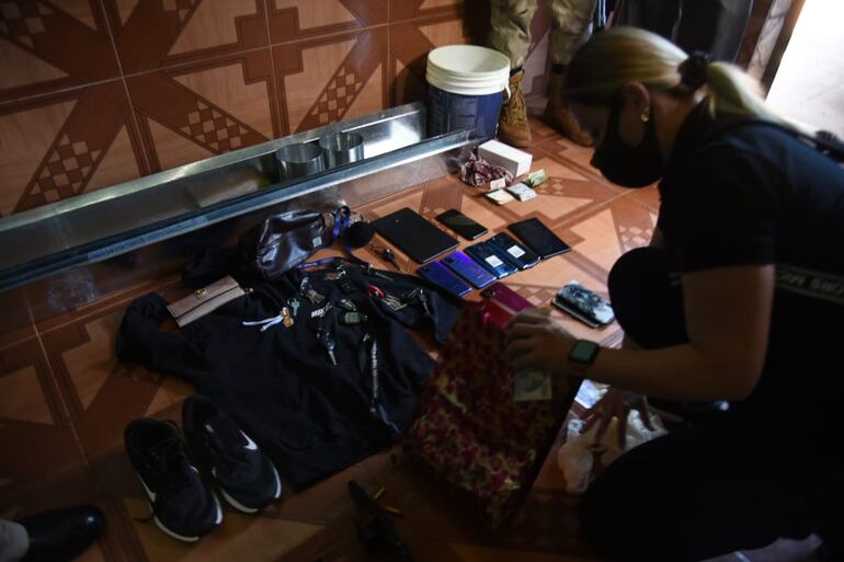 Una investigadora policial inspecciona objetos a ser incautados de una de las viviendas allanadas.