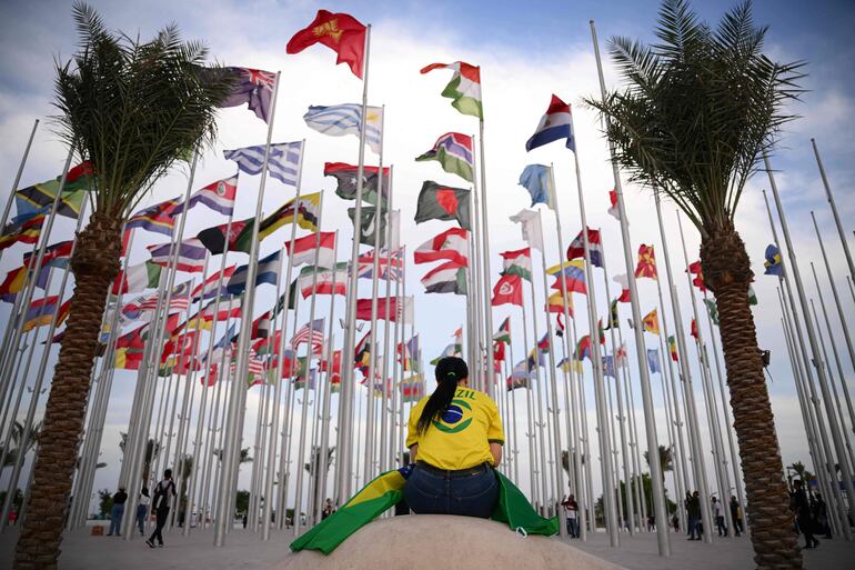 TOPSHOT - A woman seats at Flags square, in Doha on November 17, 2022, ahead of the Qatar 2022 World Cup football tournament. (Photo by Anne-Christine POUJOULAT / AFP)