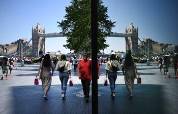 Varias personas aparecen reflejadas en una ventana en las inmediaciones del Puente de la Torre, en Londres. Reino Unido continúa con su programa de vacunación en su lucha contra la variante india de la covid19 que continúa extendiéndose por el país. E