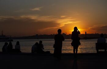 Varias personas contempla la puesta de sol sobre el Bósforo en Estambul.