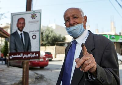 Un votante, enmascarado debido a la pandemia del coronavirus COVID-19, muestra su dedo manchado de tinta después de votar en Irbid, en el norte de Jordania.