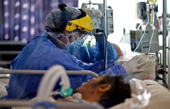 Un trabajador sanitario controla el estado de un paciente con COVID-19 en la unidad de terapia intensiva del hospital San Roque Hospital en Córdoba, Argentina.