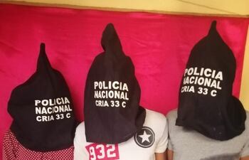 Fotografía de los tres detenidos, con capuchas, en la sede de la comisaría.