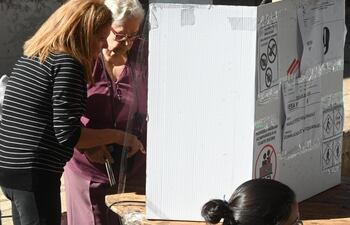 Adulta mayor siendo asistida para ejercer su voto.