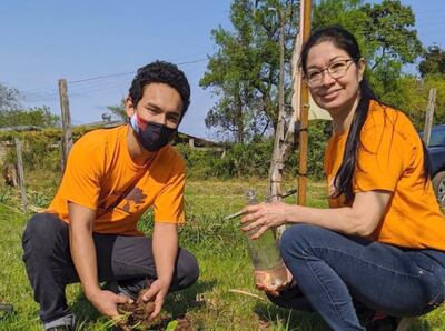 Un joven, junto a una docente,  se disponen a plantar un arbolito.