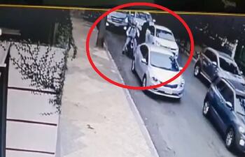 Momento en que uno de los ocupantes de la moto desciende e intenta romper la ventanilla del rodado.