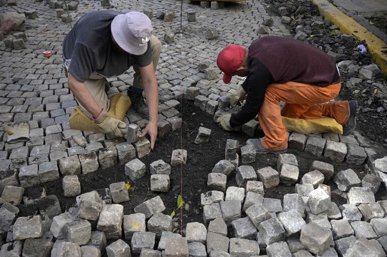 Trabajadores restauran el empredrado de una calle de San Telmo en Buenos Aires. 