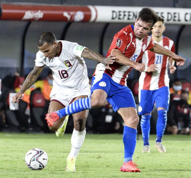El volante de Libertad Hugo Martínez en la pelea por la pelota con el venezolano Rómulo Otero. El juvenil gumarelo mostró pasta de jugador de selección.
