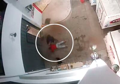 Uno de los malvivientes con un arma de fuego en mano acuesta al repartidor recién llegado, en el estacionamiento de vehículos.