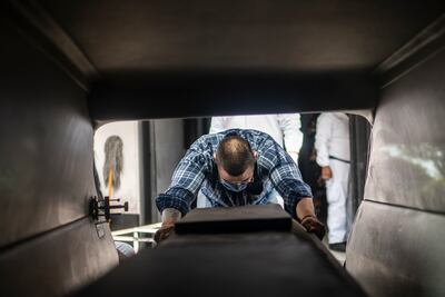 (FILES) In this file photo taken on June 1, 2020 Mauricio Navarrete, 27, unloads a coffin with a victim of COVID-19 from a hearse at a cemetery Mexico City. - Almost six months after it was first detected in Latin America, the coronavirus death toll has reached 250,000 and exacerbated the problems of poverty and inequality, threatening to undo a decade of slow social progress. (Photo by PEDRO PARDO / AFP)