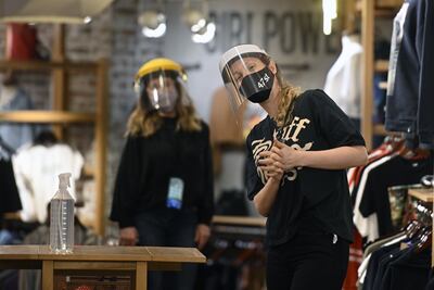 Empleadas de una tienda de ropas, con mascarillas y protectores faciales, en un centro comercial en Buenos Aires.