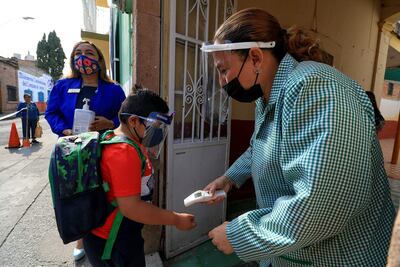 Una profesora toma la temperatura a un alumno hoy, durante el regreso a clases del preescolar Carrusel Mágico, en la ciudad de León, estado de Guanajuato (México). Escuelas del central estado mexicano de Guanajuato arrancaron este martes una prueba piloto de regreso a clases presenciales en medio de una caída nacional de contagios de covid-19 y la vacunación del personal educativo.