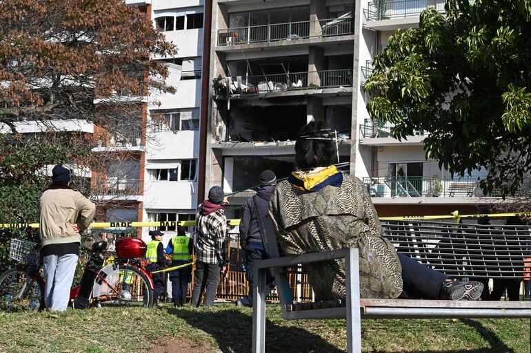 Gente observa la fachada del edificio que explotó en Montevideo. 