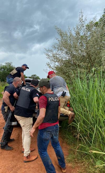 Agentes policiales de Villa Ygatimí alzan al presunto sicario herido a una patrullera.