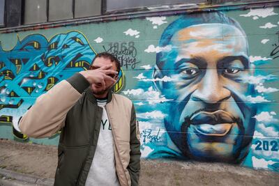 El artista Fouad Hachmi posa frente a un mural que produjo en homenaje a George Floyd y otras víctimas de abusos policiales, en Grimbergen, Bélgica.