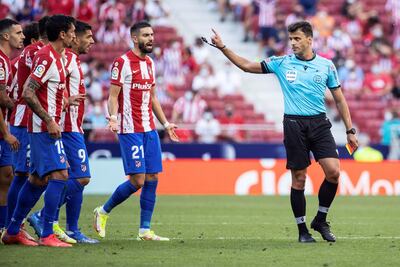 Los jugadores del Atlético de Madrid y el árbitro Gil Manzano (d), durante el partido de la quinta jornada de Liga de Primera División este sábado en el Estadio Wanda Metropolitano en Madrid.
