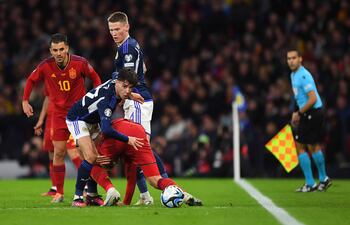 El español Dani Ceballos (y) y el escocés Scott McTominay (c) observan cómo el defensor británico Aaron Hickey disputa el balón con el hispano Mikel Oyarzabal, durante el partido de ayer en Glasgow.