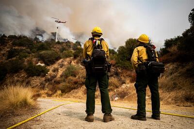 Dos bomberos observan a un helicóptero que deja caer agua sobre el fuego Bobcat, ardiendo en el Bosque Nacional de Ángeles hoy, cerca de Arcadia, California (EE.UU.).