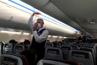 Un asistente de vuelo con mascarilla explica las precauciones de seguridad en un avión Boeing 737 MAX de American Airlines.