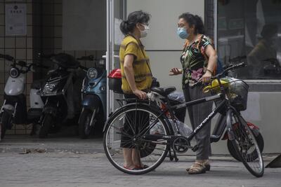 Dos mujeres con mascarillas conversan en una calle de Pekín, en China.