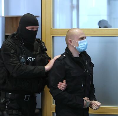 El acusado Stephan Balliet es escoltado por un policía al llegar al juzgado en Magdeburg, Alemania.