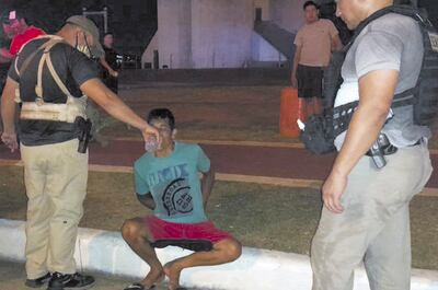 Un agente de la Senad convida agua al arrestado Cristian Paiva.