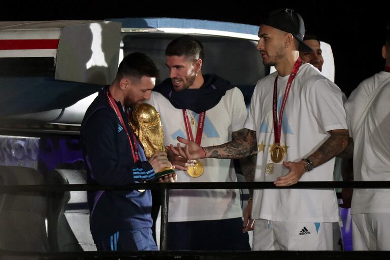 Lionel Messi bajando del avión con la Copa del Mundo en mano en el regreso de Argentina después de conquistar el Mundial Qatar 2022. 